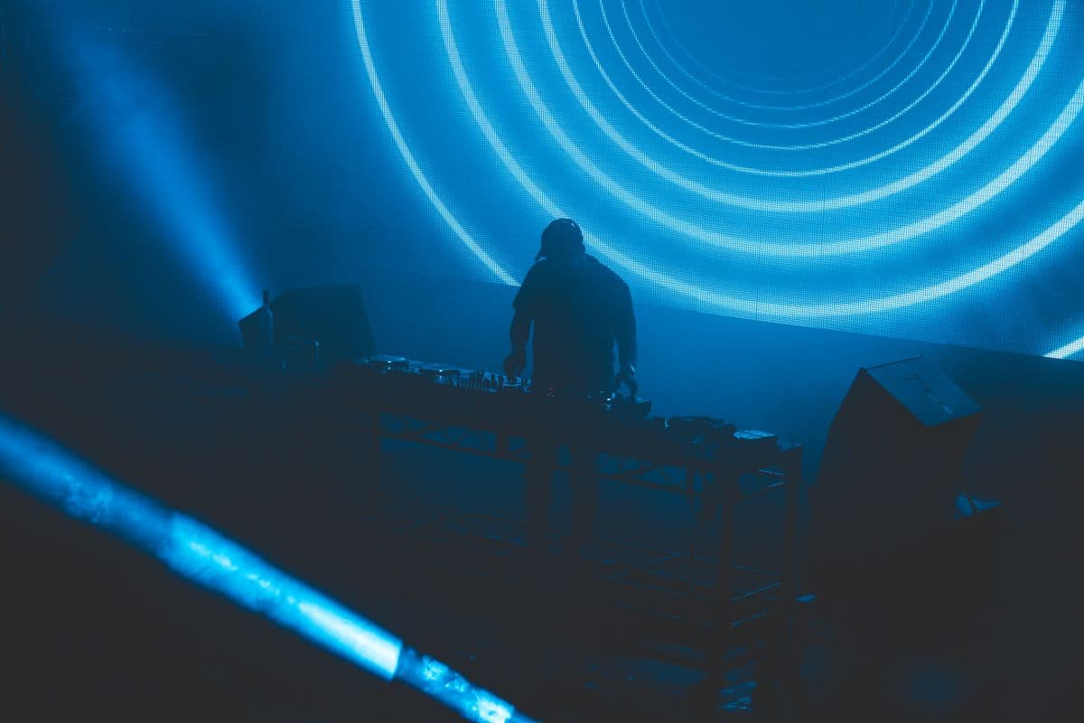 Silhouette d'un disc-jockey devant des cercles lumineux bleus