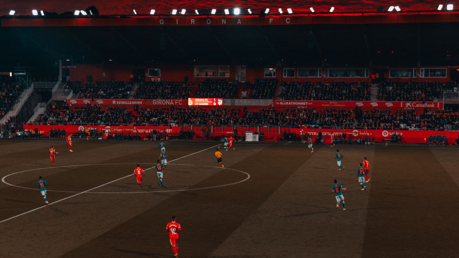 Terrain de football vu de loin pendant un match, au crépuscule